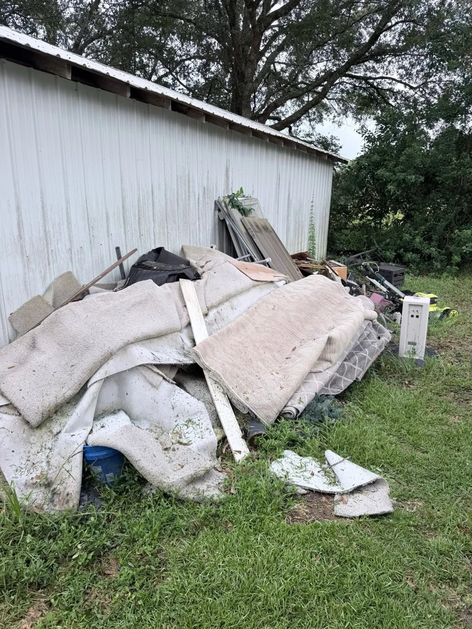 Carpet and household debris before yard cleanup